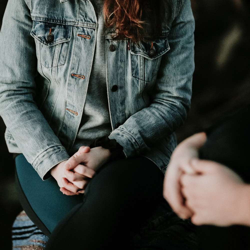 Woman with clasped hands receiving counselling